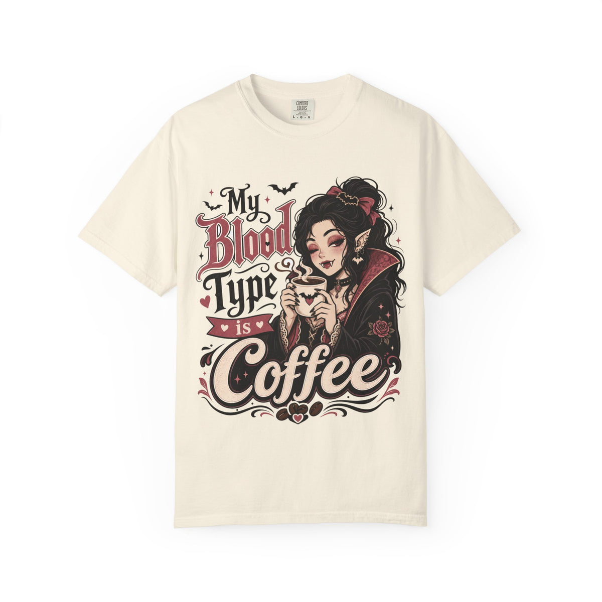 An off-white short-sleeve crewneck t-shirt featuring a gothic-style graphic print of a vampire woman and the text 'My Blood Type is Coffee' in stylized red and beige lettering.