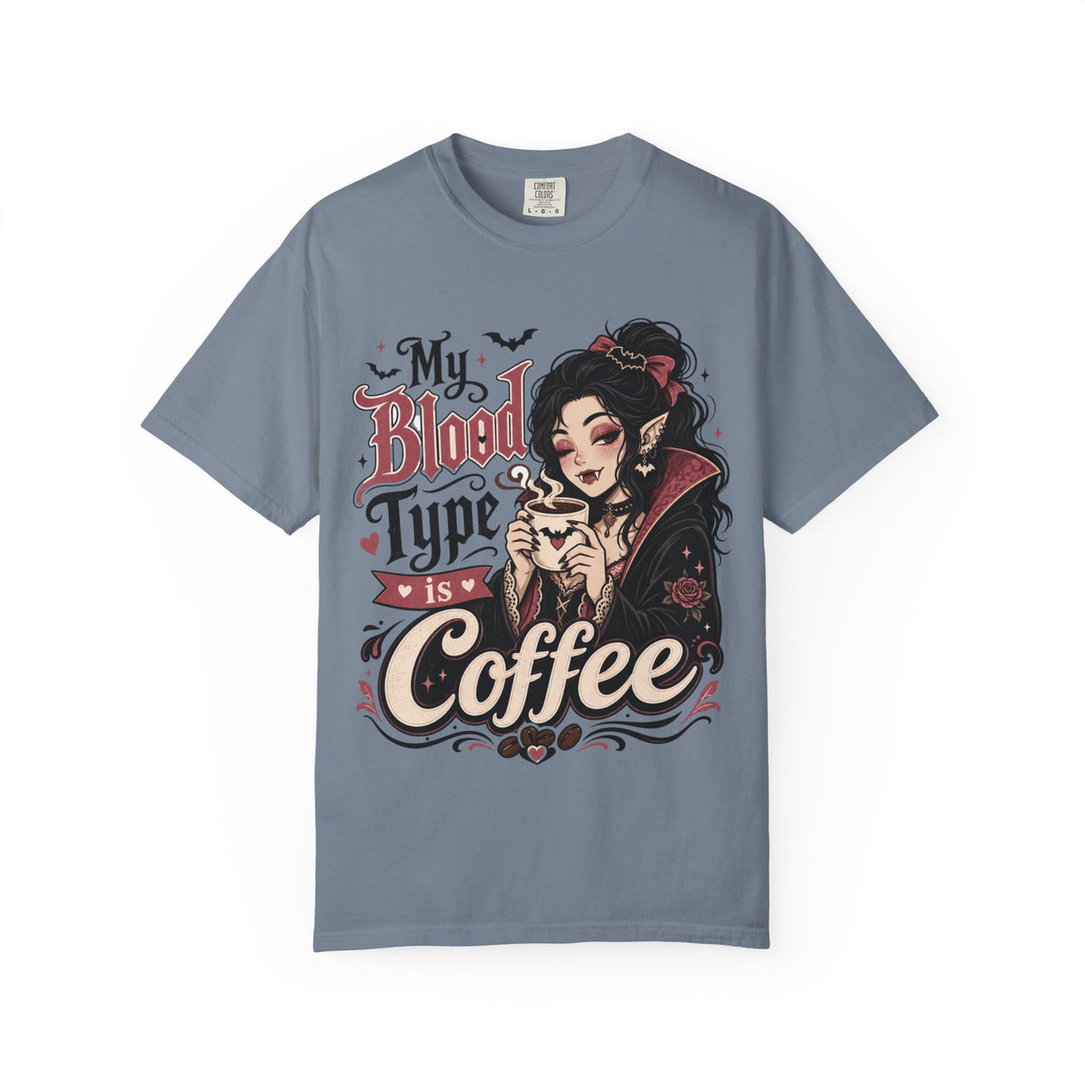 A slate blue short-sleeve crewneck t-shirt featuring a gothic-style graphic print of a vampire woman and the text 'My Blood Type is Coffee' in stylized red and beige lettering.