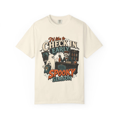 An off-white short-sleeve crewneck t-shirt featuring a colorful graphic print on the front with the text 'I'd like to CHECK IN EARLY SPOOKY SEASON' and illustrations of a skeleton concierge, a ghost, and a haunted house.