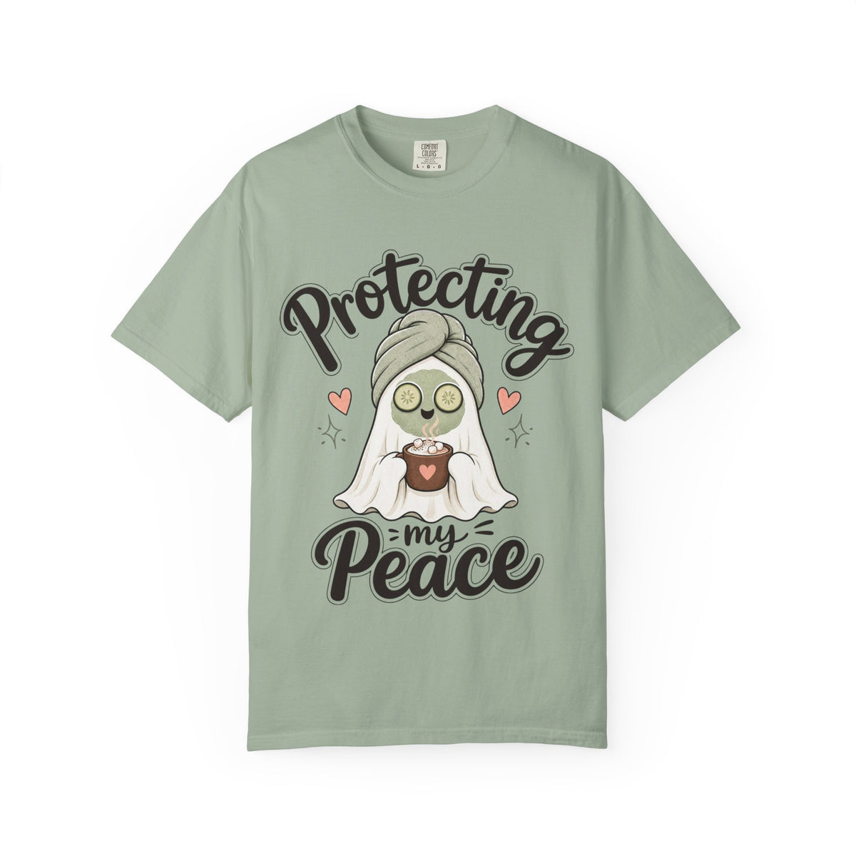 A sage green short-sleeve crewneck t-shirt featuring a graphic of a cartoon ghost wearing a green head wrap, spa mask and holding a cup, with the text 'Protecting my Peace' written in black script.