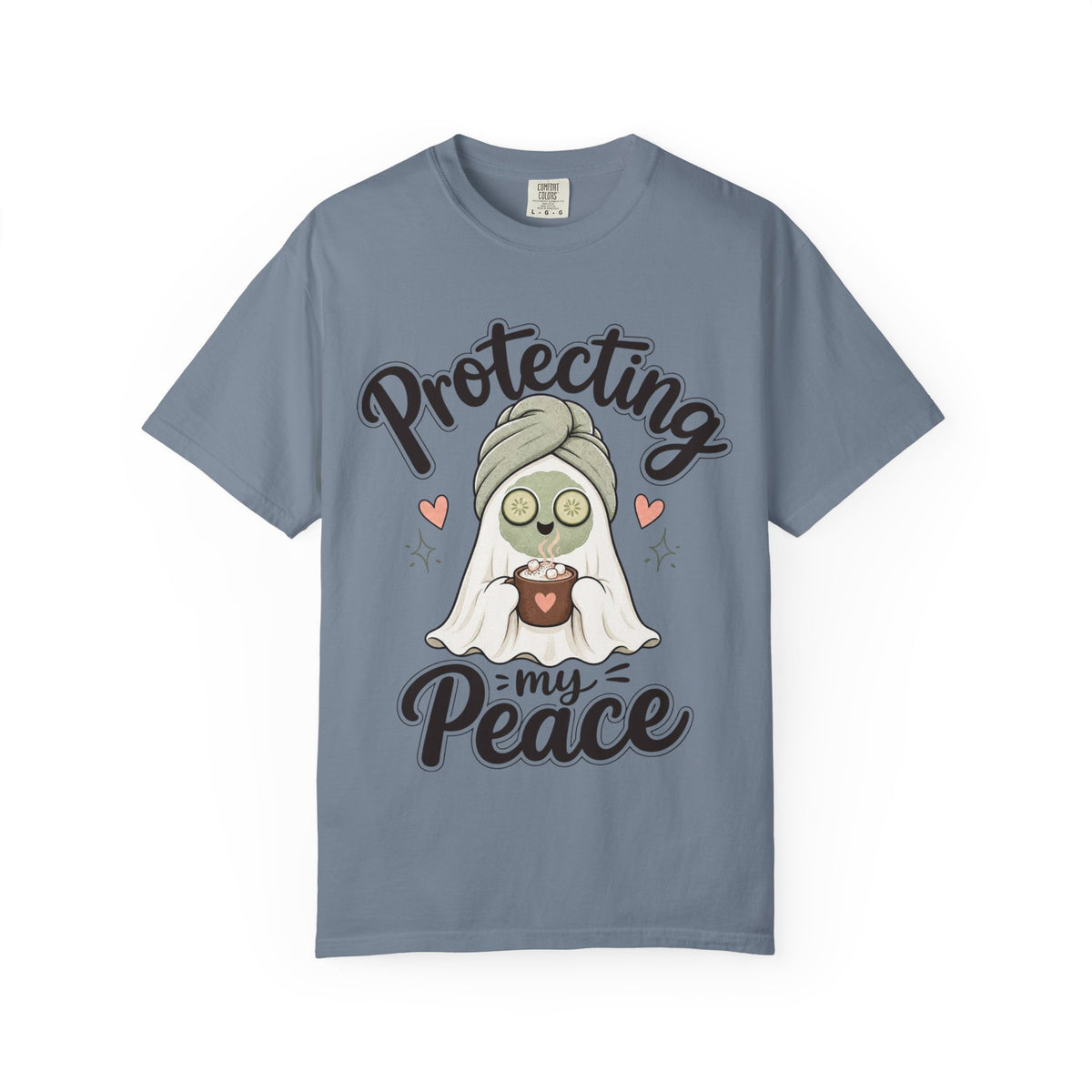 A slate blue short-sleeve crewneck t-shirt featuring a graphic of a cartoon ghost wearing a green head wrap, spa mask and holding a cup, with the text 'Protecting my Peace' written in black script.