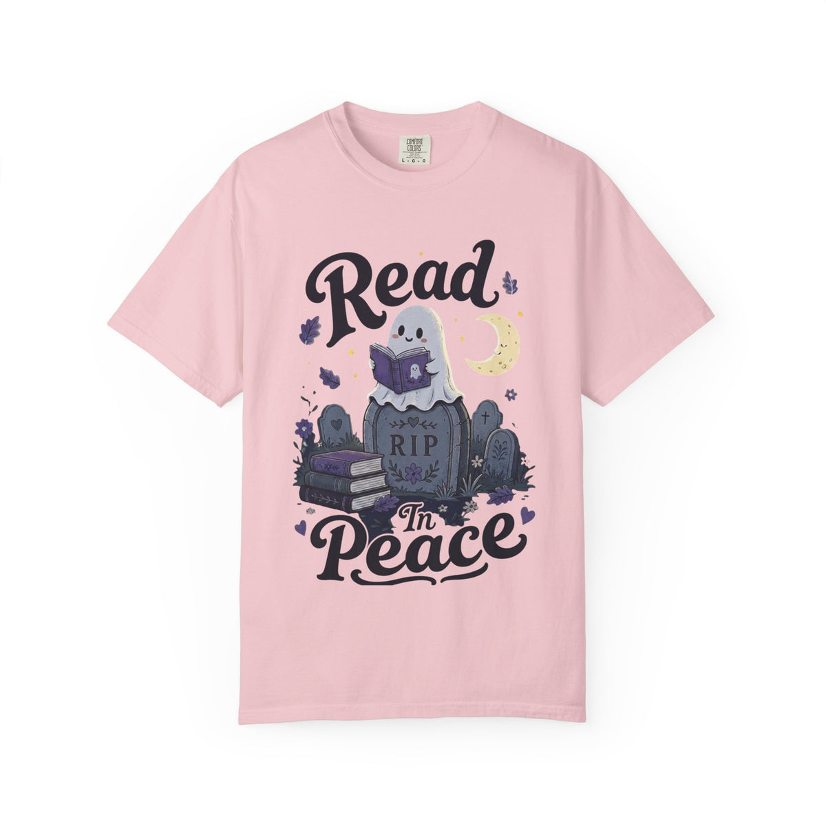 A pink short-sleeve crewneck t-shirt featuring a cute Halloween graphic of a ghost reading a book on top of a tombstone that says 'RIP', with the words 'Read In Peace' written in stylized lettering.