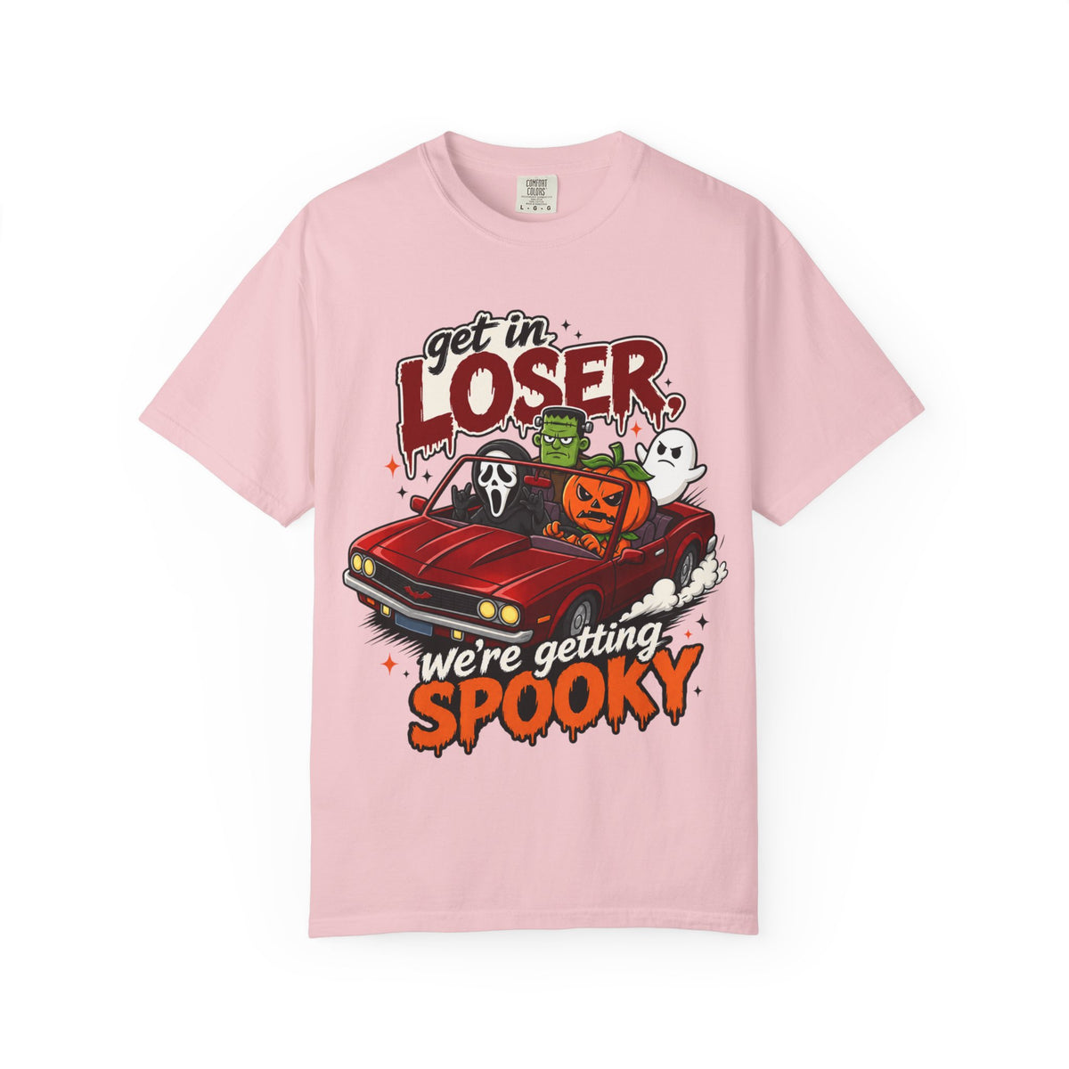 A pink short-sleeve crewneck t-shirt featuring a colorful Halloween graphic on the front showing a red convertible car with ghosts, a pumpkin, and Frankenstein, with the text 'Get in LOSER, we're getting SPOOKY'.