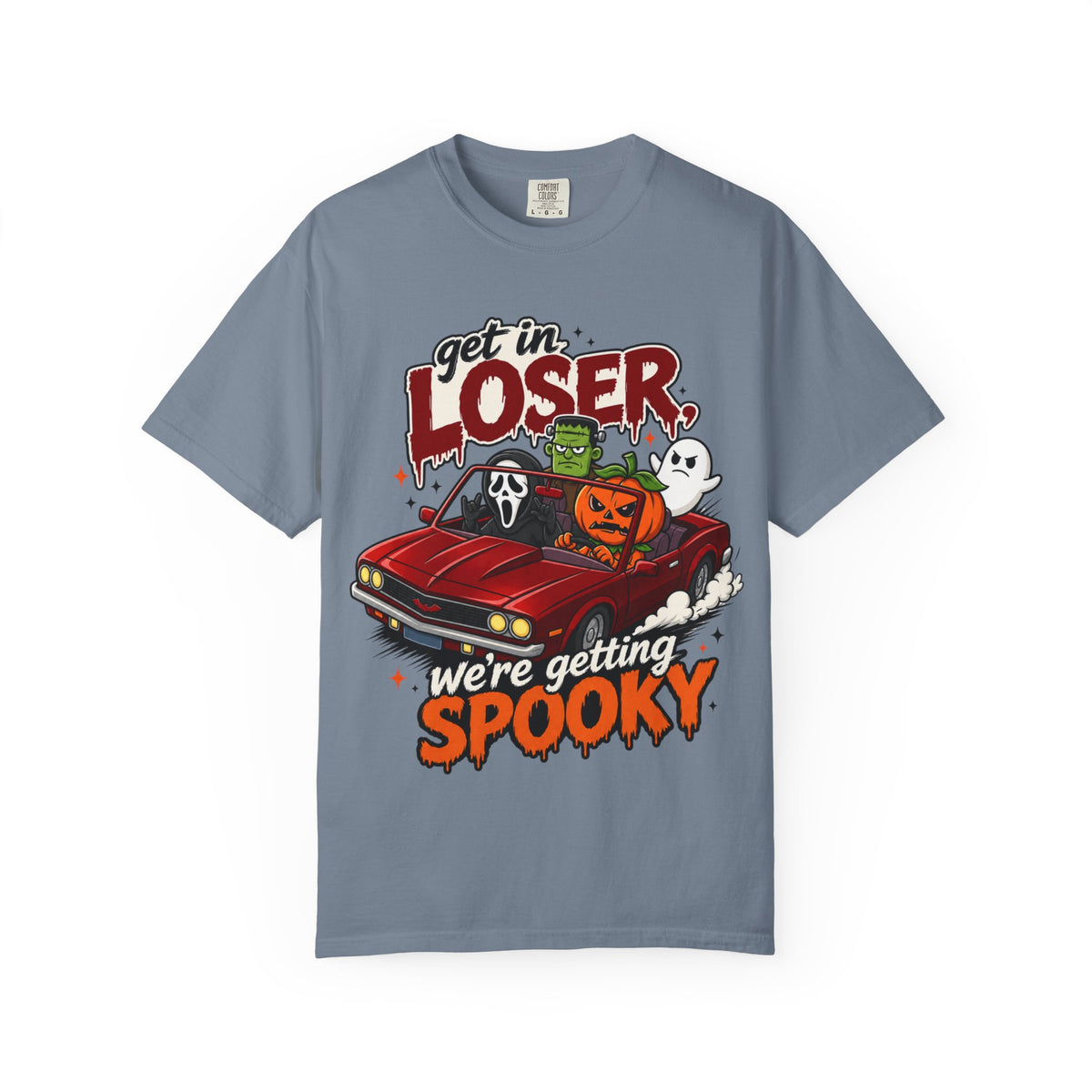 A slate blue short-sleeve crewneck t-shirt featuring a colorful Halloween graphic on the front showing a red convertible car with ghosts, a pumpkin, and Frankenstein, with the text 'Get in LOSER, we're getting SPOOKY'.