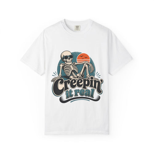 A white short-sleeve crewneck t-shirt featuring a retro graphic of a skeleton sitting next to an orange sun, with the text 'Creepin' it real' printed below.