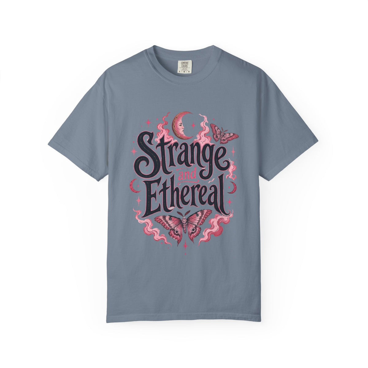 A slate blue short-sleeve crewneck t-shirt featuring a central graphic with the words 'Strange and Ethereal' in a dark gothic font, surrounded by pink and red butterflies, crescent moons, and sparkles.