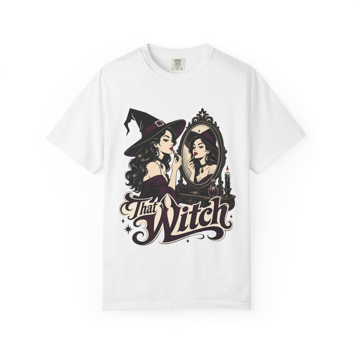 A white short-sleeve crewneck t-shirt featuring a graphic print of a witch applying lipstick in front of a mirror, with the text 'That Witch' written below in a stylized font.