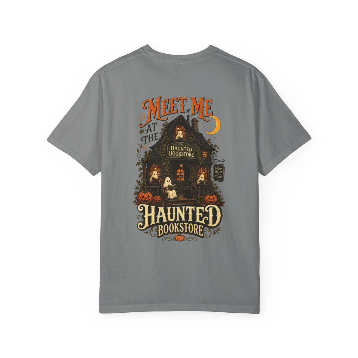 A gray short-sleeve t-shirt with a detailed graphic on the front depicting a haunted bookstore at night, complete with pumpkins, a ghost, and orange text reading 'MEET ME AT THE HAUNTED BOOKSTORE'.