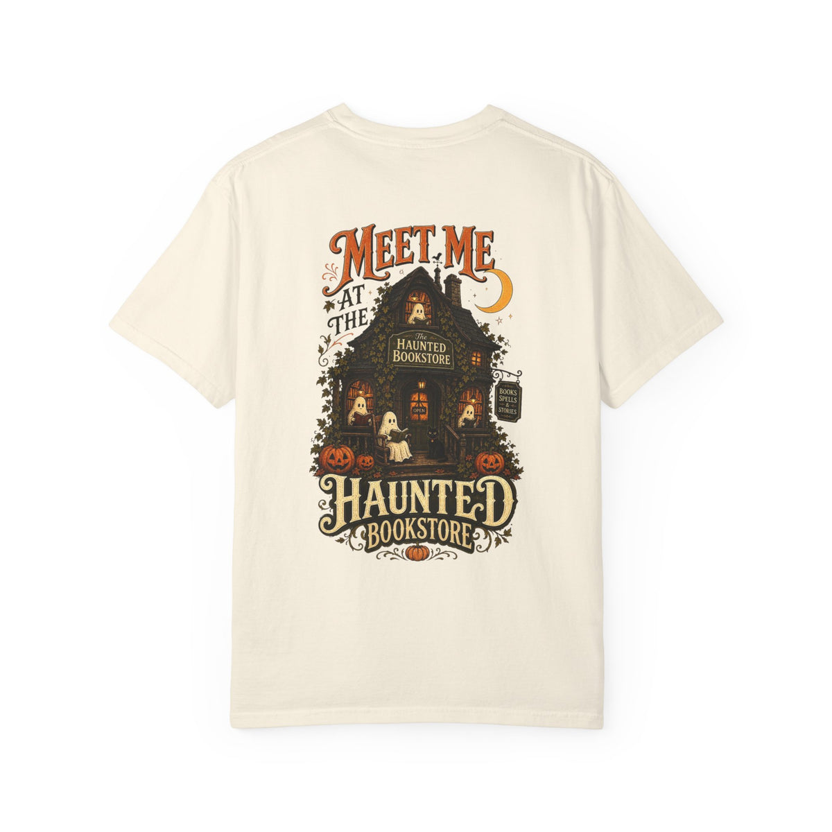 An off-white short-sleeve t-shirt with a detailed graphic on the front depicting a haunted bookstore at night, complete with pumpkins, a ghost, and orange text reading 'MEET ME AT THE HAUNTED BOOKSTORE'.