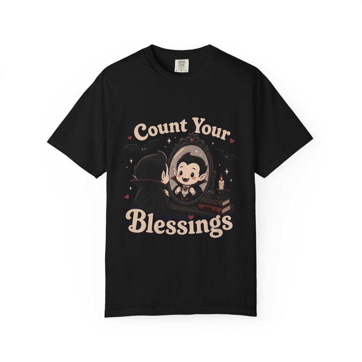 A black short-sleeve crewneck t-shirt featuring a cute cartoon graphic of a vampire smiling at mirror, with the text 'Count Your Blessings' in a peach-colored font.