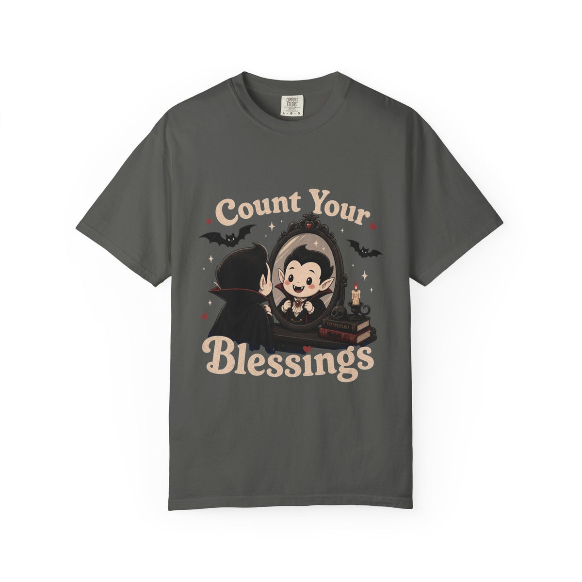 A dark gray short-sleeve crewneck t-shirt featuring a cute cartoon graphic of a vampire smiling at mirror, with the text 'Count Your Blessings' in a peach-colored font.