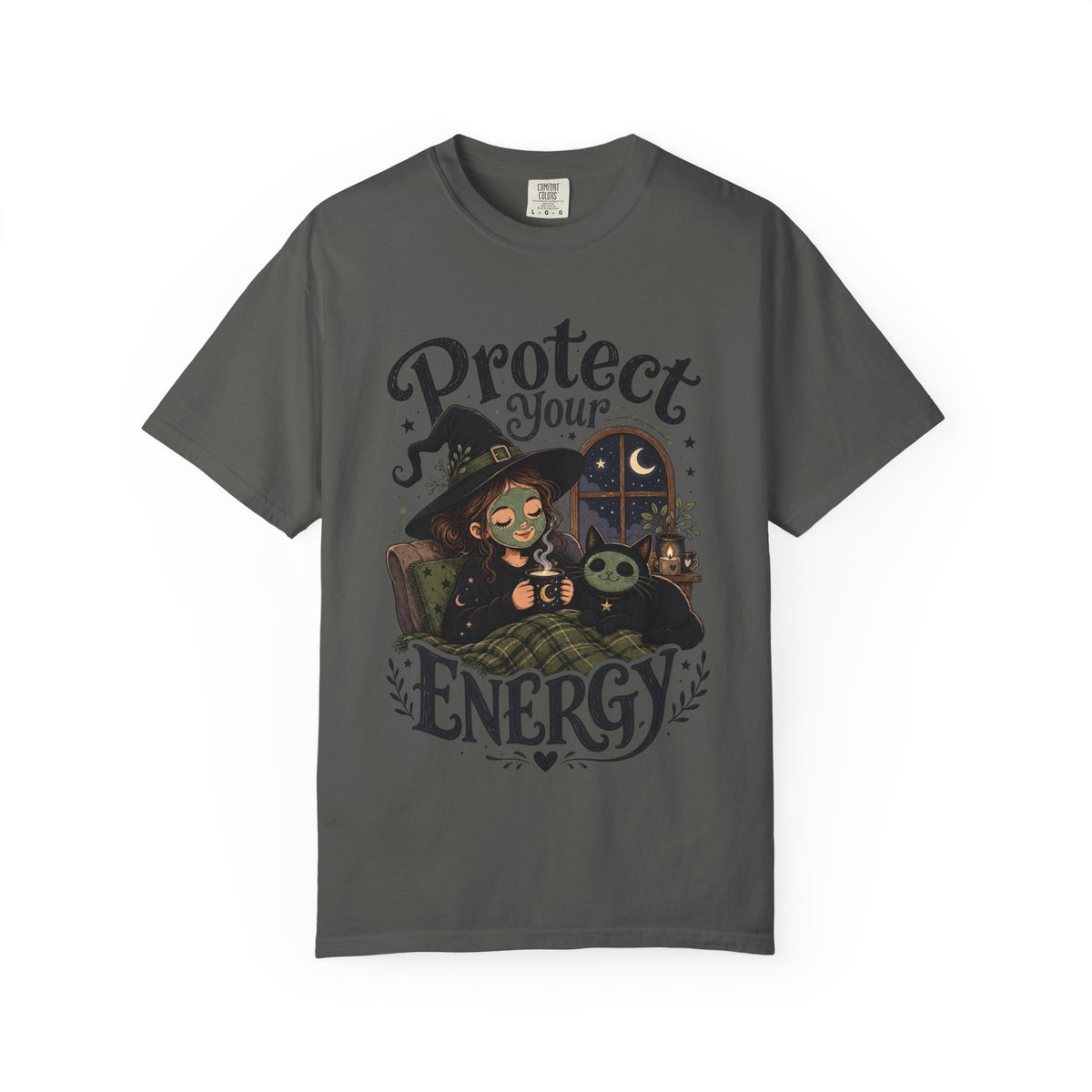 A dark gray short-sleeve crewneck t-shirt featuring a graphic showing a cartoon witch sitting in bed with her cat, both wearing spa face masks, under a window with crescent moon, with the text 'Protect Your Energy' written in a gothic font.
