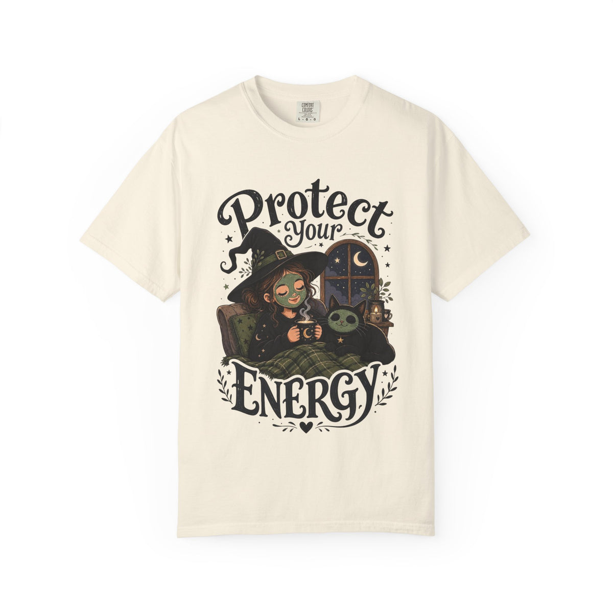 An off-white short-sleeve crewneck t-shirt featuring a graphic showing a cartoon witch sitting in bed with her cat, both wearing spa face masks, under a window with crescent moon, with the text 'Protect Your Energy' written in a gothic font.